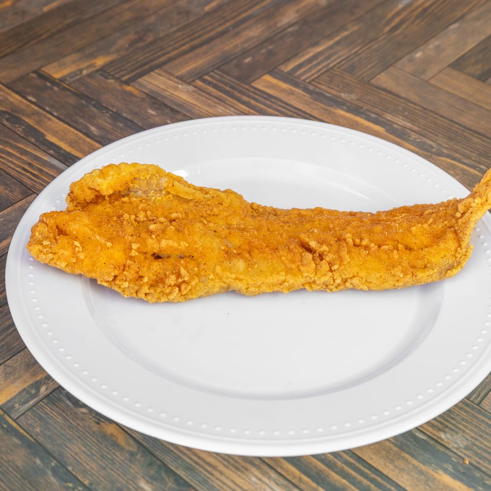 Crispy golden fried fish fillet served on a simple white plate.