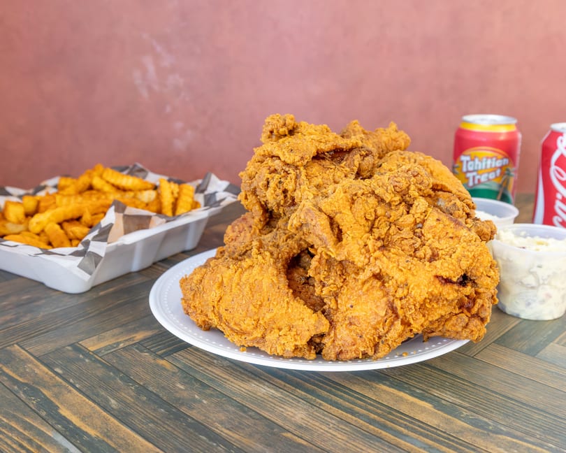 Generous serving of crispy fried chicken, crinkle-cut fries, coleslaw, and two sodas.