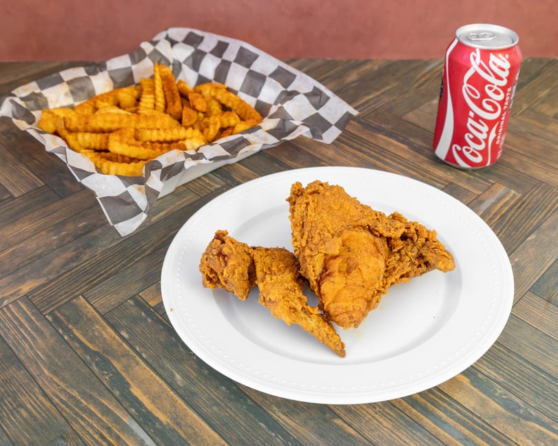 A plate of fried chicken with a side of crinkle-cut fries and a Coca-Cola.