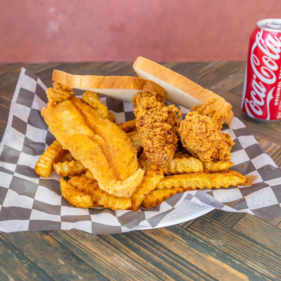 Golden fried fish, chicken, and seasoned fries with white bread and a Coca-Cola.